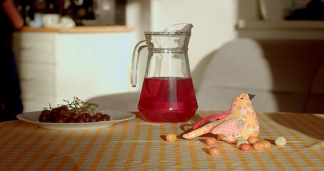 A vibrant red drink is served in a decorative jug with delicious snacks on a cheerful tablecloth, creating an inviting atmosphere for a delightful casual dining experience