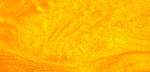 Shimmering gold abstract background. Liquid gold texture waves and swirls. Beautiful shiny yellow texture with glitter. Liquid gold metallic paint close-up.