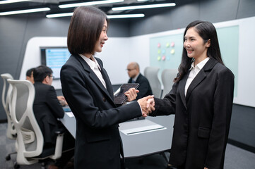 Businesswomen standing pose, group meeting around table in modern office, documents, laptops and handshake, everyone brainstorming, planning sales, digital marketing and growth strategies.