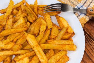 French fries on dish with fork, fragment close-up