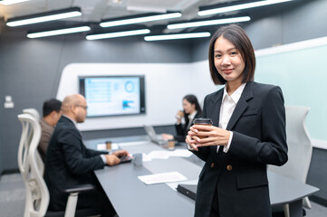 Beautiful young businesswoman meeting in modern office with documents, laptop and coffee to keep her awake. Everyone brainstorming, planning sales, digital marketing and growth strategies.