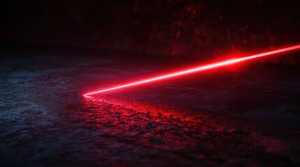 Red laser beam on dark surface.