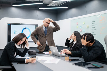 Male software developer meeting in modern office with stressed employees, documents, laptops, sales planning, digital marketing and growth strategies, analysis with colorful charts and graphs.