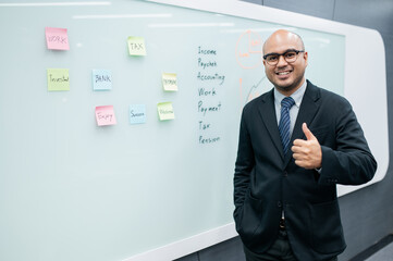 Obraz premium Businessman smiling, looking at camera, post-it notes, sales planning, digital marketing, growth strategy, marketing goals, analysis with colorful charts and graphs.