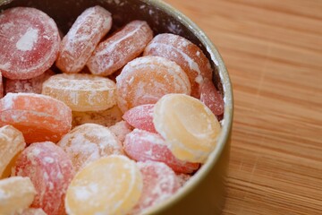 Tin box full of different flavours hard drop candies on a wooden background. Close-up