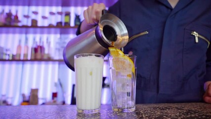 Person pouring cold drinks into glasses with ice and orange slices