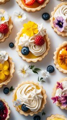 Set of colorful tartlets with lemon, berry, and apricot filling decorated with small bright flowers. Artistic flat lay.