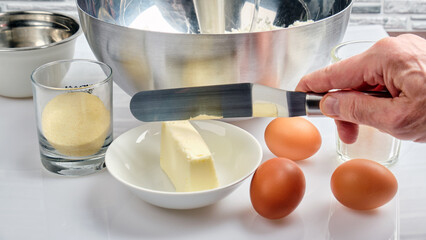 Homemade Pudding Technology - a cook measures out a piece of butter with a metal spatula to add to dough