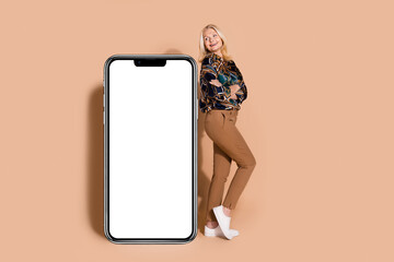 Photo portrait of blonde mature age business woman in stylish shirt folded arms looking at touchscreen isolated on beige color background