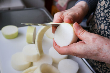 大根の皮を包丁で剥くシニア女性の手元