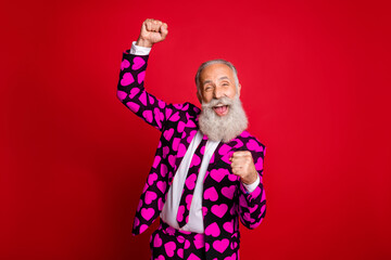 Photo of funky mature guy amour cupid character role raising fists excited party beginning wear stylish hearts pattern suit costume shirt tie isolated vivid color background