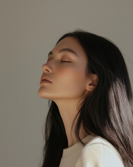 A close-up photograph of a teenage girl, young woman with long, straight black hair, posing for a beauty photoshoot. The image highlights her smooth, shiny skin texture, capturing a glossy and radiant