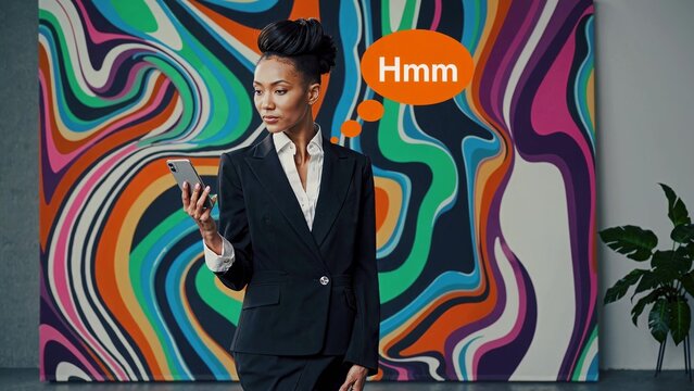 Pensive businesswoman wearing a suit and holding a smartphone, standing in front of a colorful abstract painting and thinking hmm in an art gallery