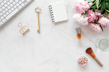 Flatlay office desk with pink peony flowers and female accessories