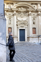 During a walk, woman inspects an ancient building decorated with sculptures