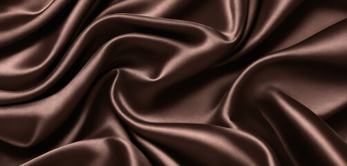 Fototapeta premium Smooth wavy dark chocolate silk fabric with soft pleats. Fabric texture.