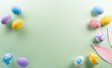 Easter party concept. Top view of easter bunny ears and colorful eggs on pastel background with copyspace for the text.