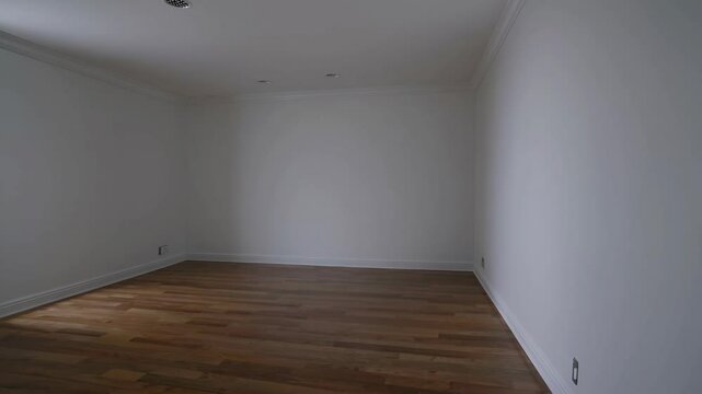 Wide-angle video shot of an empty room with wooden floors and white walls, capturing a minimalist and spacious interior design concept.