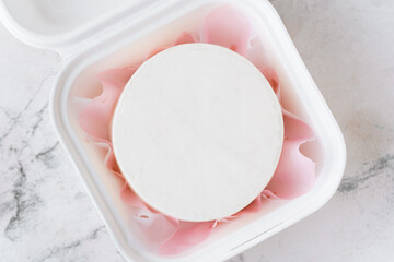 Clean white little bento cake without decoration in a gift box with pink paper inside. Cake mockup with a free space for your own decoration on the white marble background
