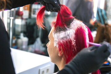 master hairdresser colorist dyes the roots of a woman with red hair