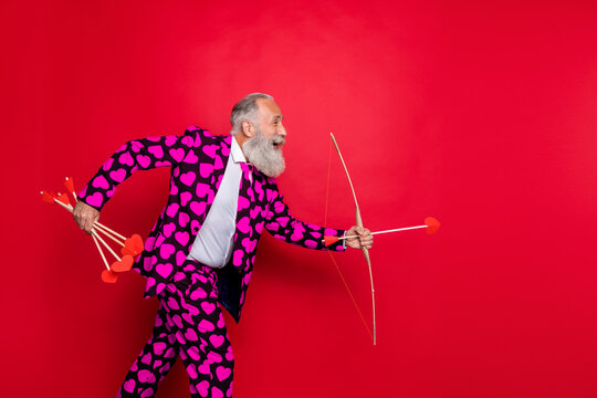 Profile photo of funky crazy aged man guy cupid see nice couple going to shoot love bow arrow wear hearts pattern suit shirt tie pants isolated red color background