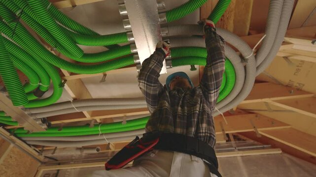 Construction worker installs air condition duct in residential ceiling during home renovation project