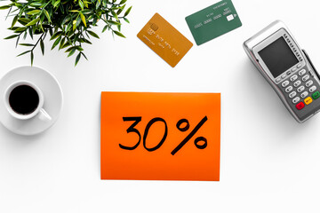Sales concept with discount sing. Online shopping - white table with POS payment terminal and credit cards, top view