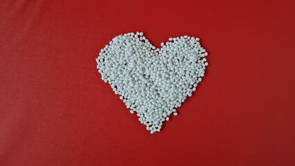 White granules are collected in a heart shape on a red background