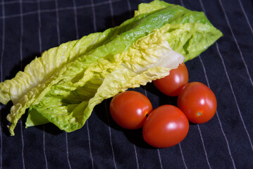 Washed cherry tomatoes and lettuce on dark blue towel in the kitchen