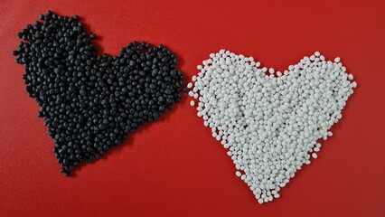 White and Black granules are collected in the shape of a heart on a red background