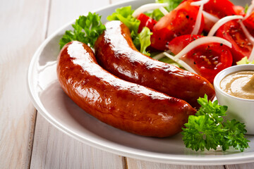 Grilled sausages with fresh salad, ketchup and mayonnaise served on white wooden table	