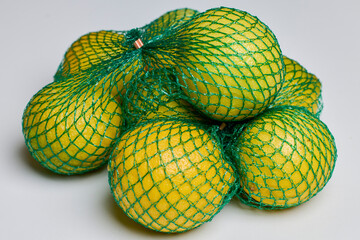 organic lemons in a green net on a table