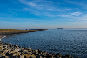 A scenic view of the coastline of Schiermonnikoog with the harbor in the distance, calm waters, and a clear sky