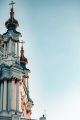 Side view of a baroque church (St. Andrew's Church) with golden domes and ornate white columns...