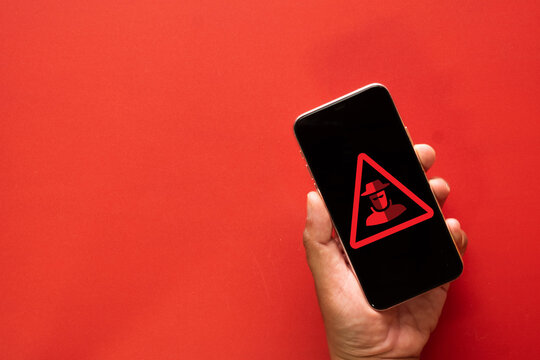 Smartphone screen with hacker icon and attention sign, cybersecurity risk, data security, hacking warning, online fraud, cyber attack alert, privacy breach, internet safety, digital crime.