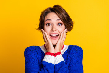 Photo portrait of pretty young girl admire touch cheeks shocked wear trendy blue knitwear outfit isolated on yellow color background