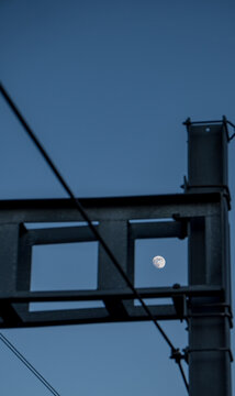 Full Moon Framed by Industrial Structure Against Dark Blue Sky