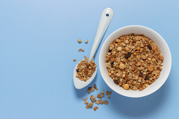 Bowl with oat granola on light blue background with copy space. Food breakfast background top view