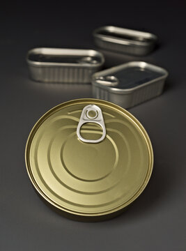 Close up of metallic food cans with pull tab lids on gray background