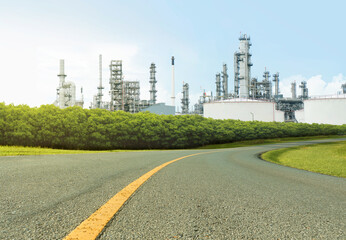 Asphalt road and Oil refinery plant with lush green trees and blue sky, large Oil and gas petrochemical industrial, Refinery factory oil storage tank and pipeline, Ecosystem and good environment.