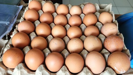 a number of fresh eggs displayed in a stall selling vegetables and meat