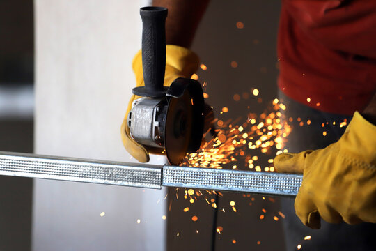 Man cutting profiles for steel frame with grinder