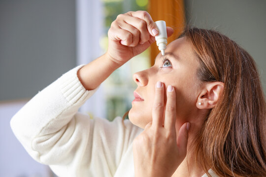 Young woman putting eye drops