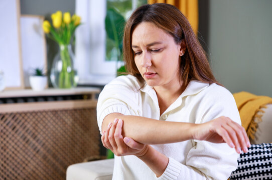 Young woman suffering from pain in elbow at home