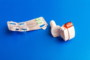 COPD or Asthma medication instruments a capsule Inhaler on blue background. Inhaler or bronchodilator and medical powder capsules for prevention and treatment of bronchitis or asthma.