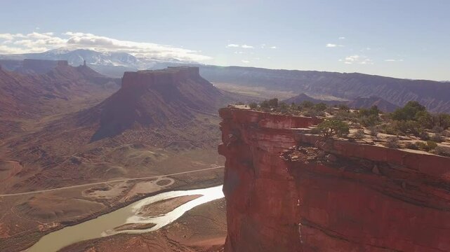 Three people base jumping off tall southern Utah rocky cliff - cinematic drone shot