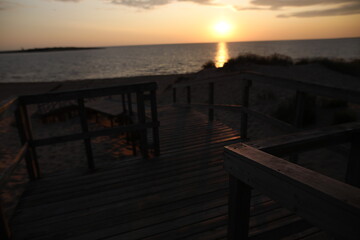 Obraz premium A pier heading down to the beach during sunset