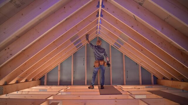 Home renovation in progress as worker measures and prepares attic space for improvement