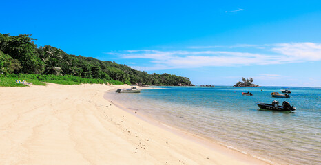 Serene beach in Seychelles with clear waters and boats anchored near the shore