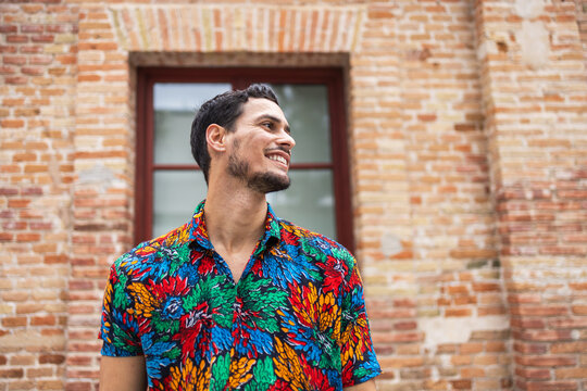 Vibrant Cuban Man Smiling in Colorful Shirt Against Brick Wall